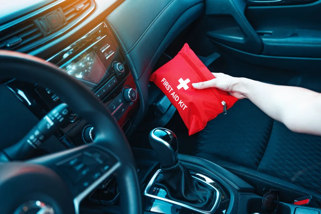 Female hand taking red first aid kit from the car glove box